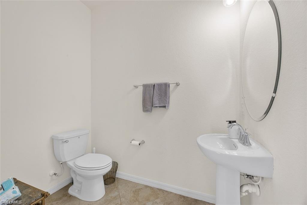 Pedestal sink with chrome faucet, oval mirror, and a wall-mounted light fixture