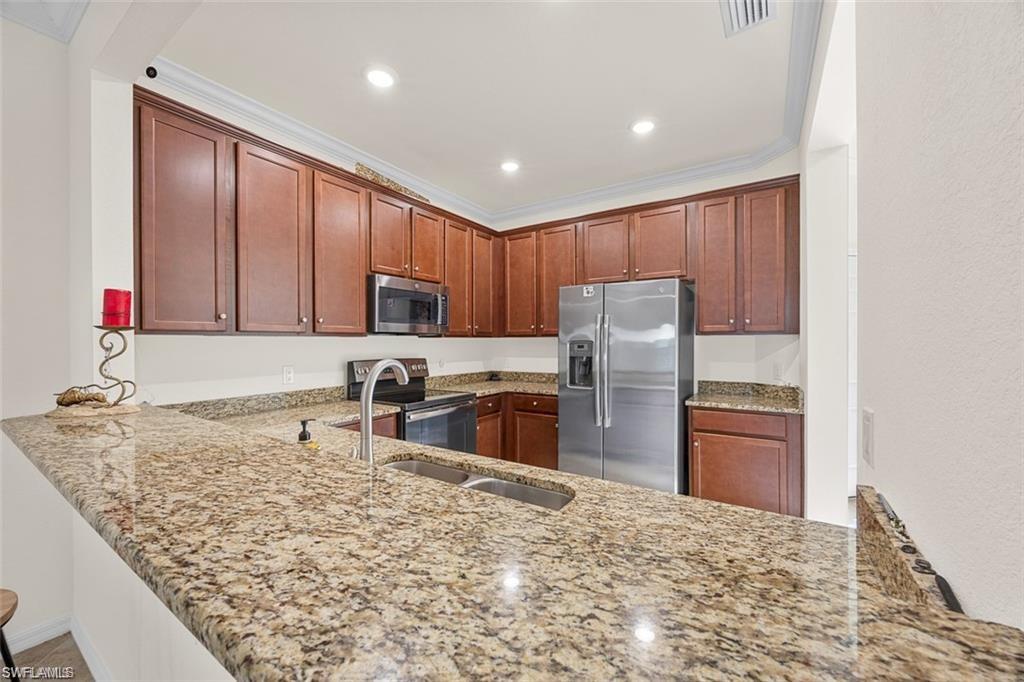 Kitchen featuring wood cabinetry, stainless steel appliances, recessed lighting, and stone countertops