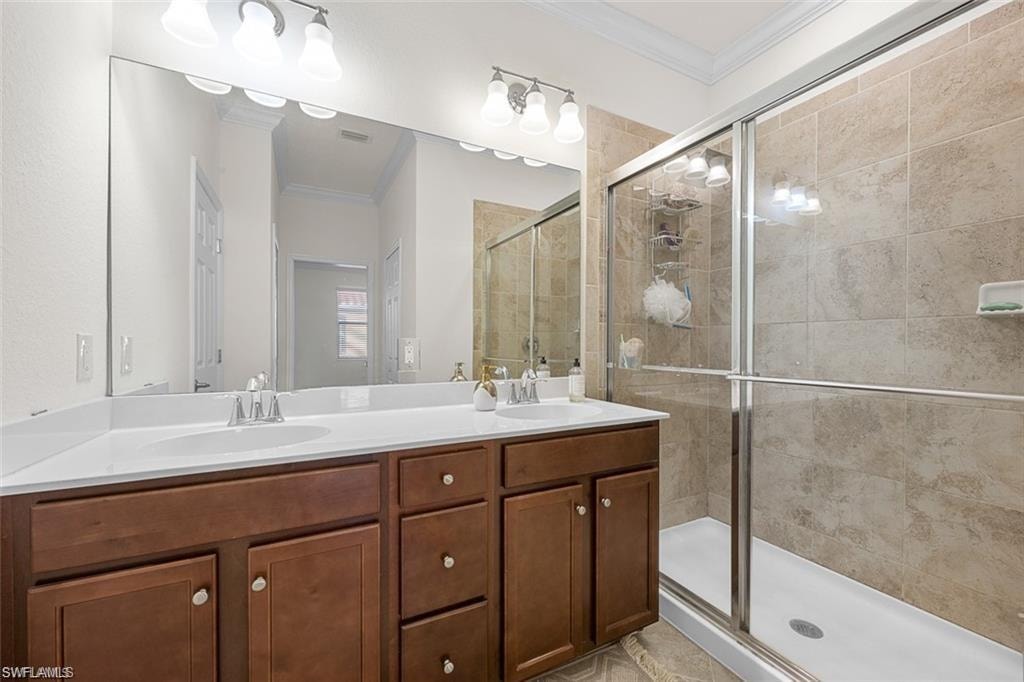 Dual vanity with white undermount sinks, wood-finish cabinetry, and a large wall-mounted mirror