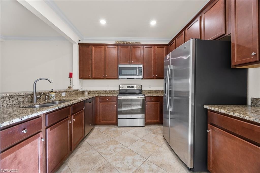 Kitchen featuring wood-finish cabinetry, granite countertops, stainless steel appliances, and tiled flooring