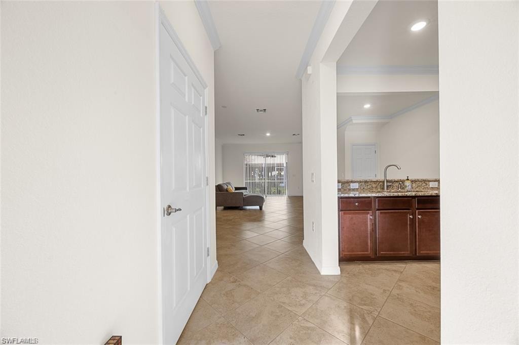 Tiled flooring throughout, recessed lighting, crown molding, and a built-in wet bar with a countertop and sink