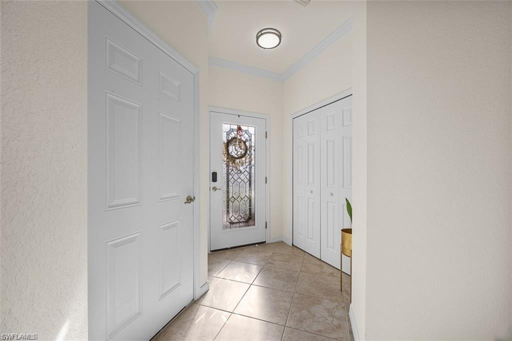 Tile flooring, front entry door with decorative glass, wall-mounted light fixture, white interior doors