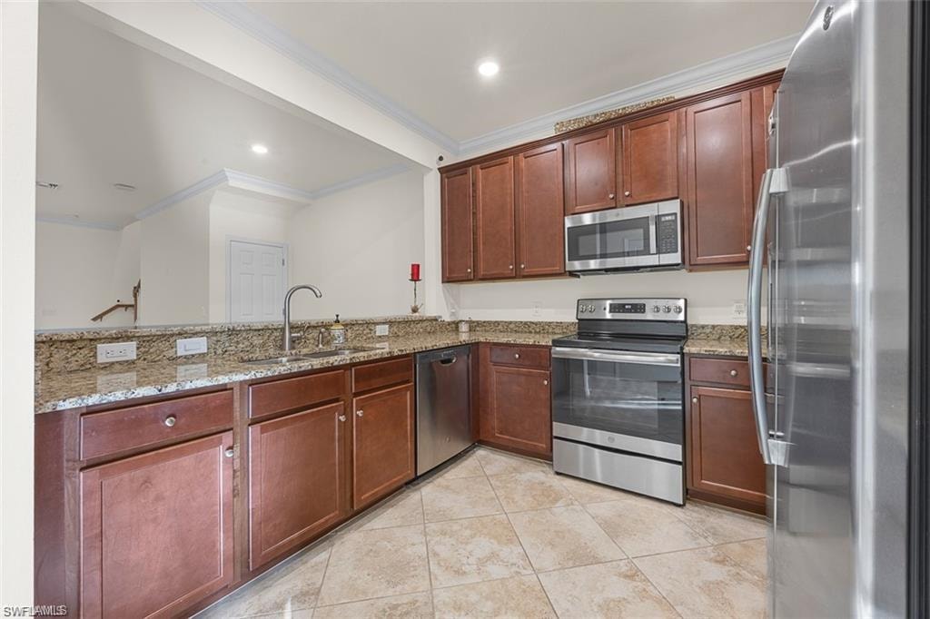 Kitchen featuring wood-finish cabinetry, stone countertops, stainless steel appliances, and tiled flooring