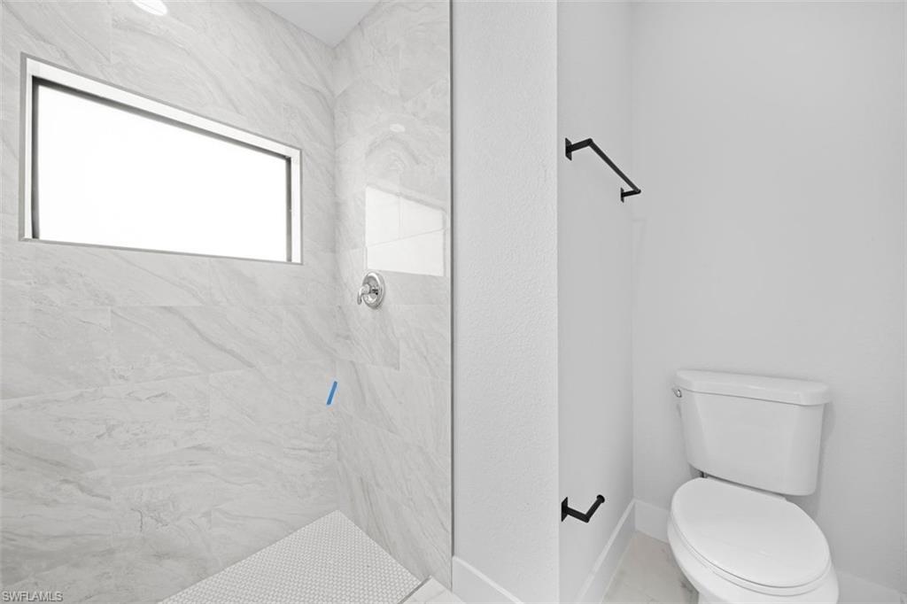 Walk-in shower with large format tile surround, horizontal accent window, and coordinating mosaic tile flooring