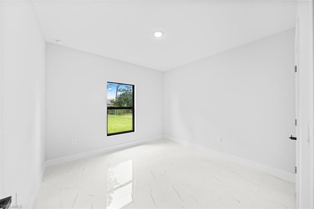Recessed ceiling lighting, a single window with black trim, and light-toned tile flooring