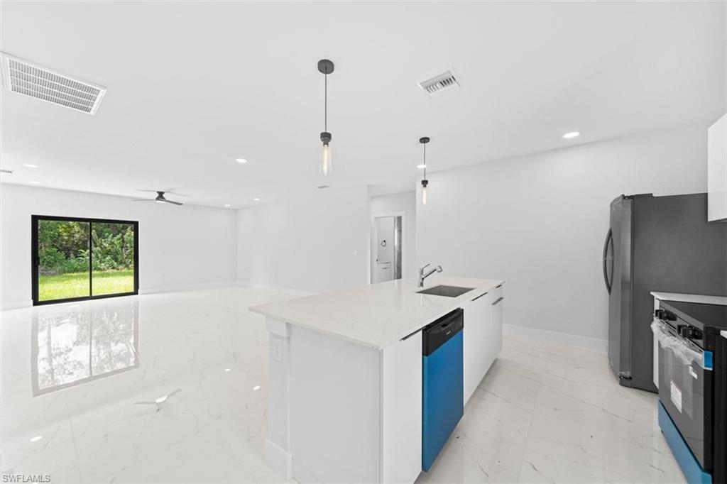 Open-concept kitchen and living area featuring white tile flooring, white walls, and recessed lighting