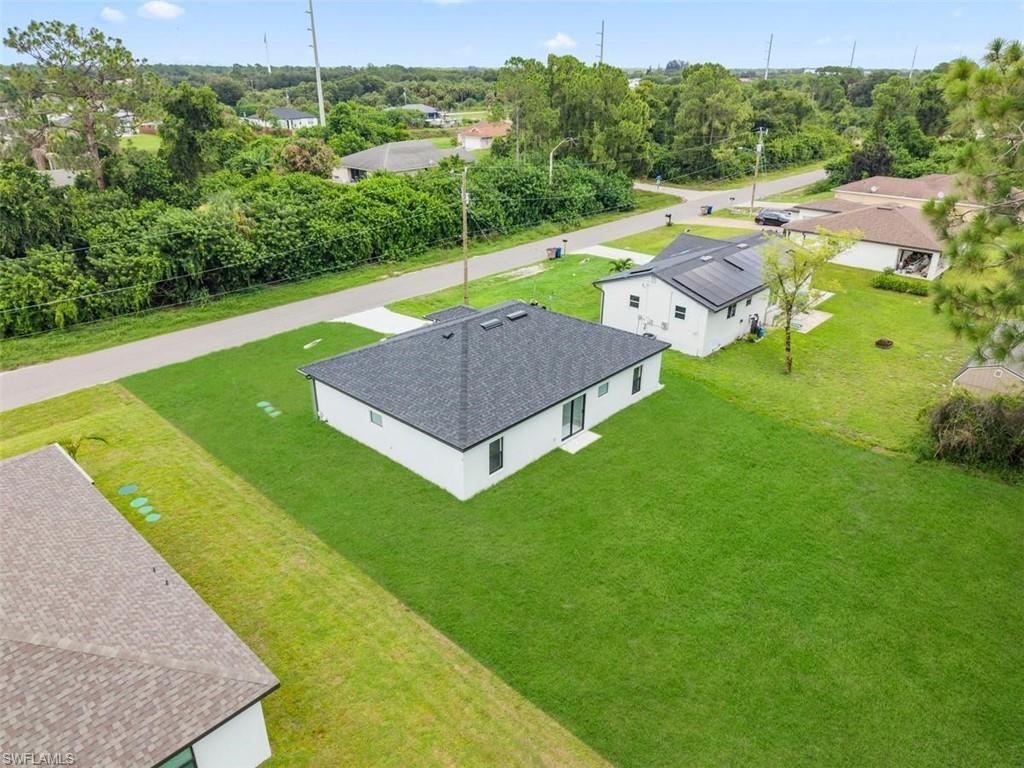 White exterior with dark roof, expansive green lawn, and paved driveway