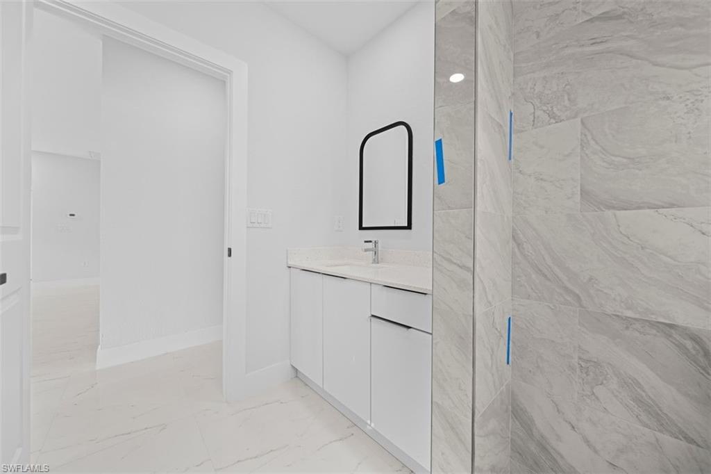 White vanity with undermount sink, countertop, and matte black framed mirror