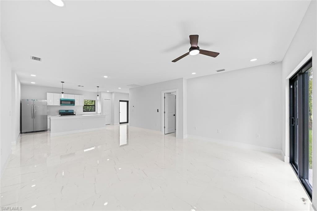 Open-concept living space with large format tile flooring, recessed lighting, and a ceiling fan