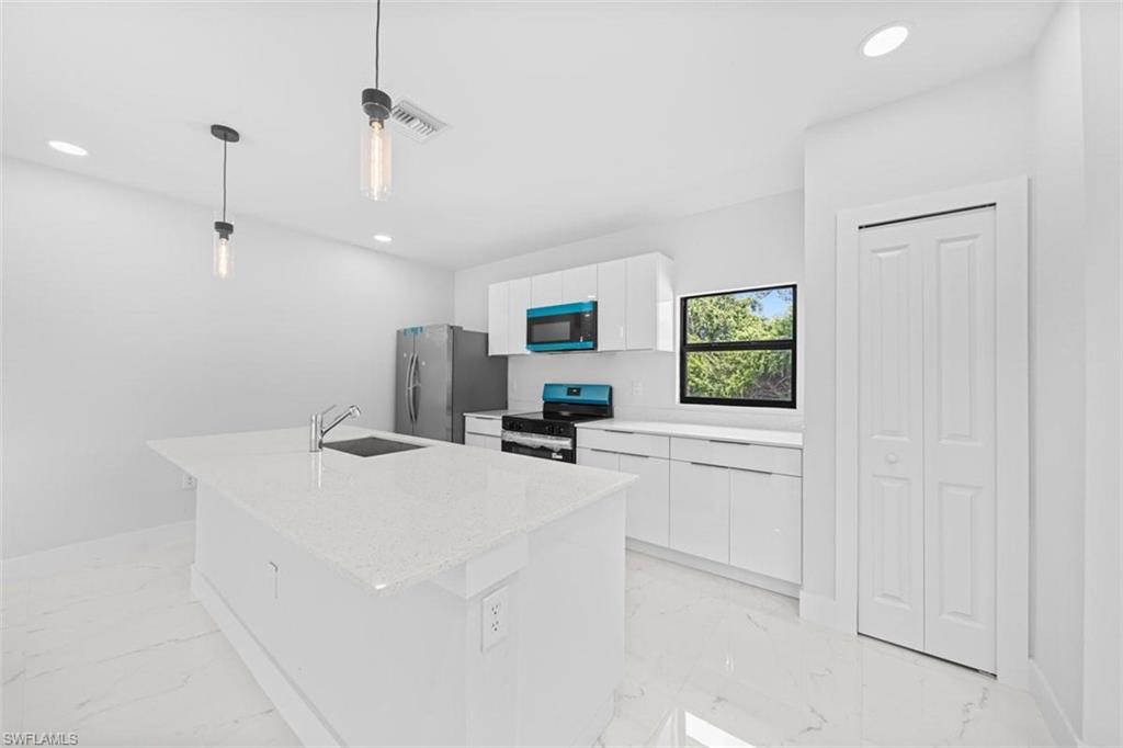 Contemporary kitchen featuring an island with an undermount sink, white cabinetry, integrated appliances, and recessed lighting