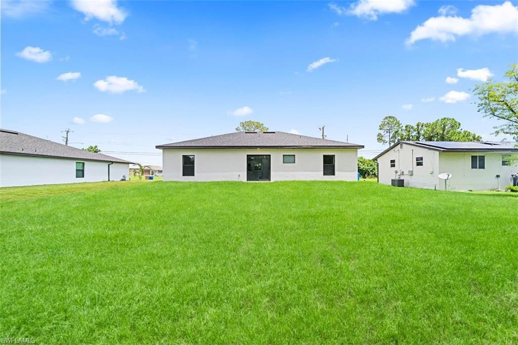 Expansive green lawn with a white stucco exterior and dark-framed windows