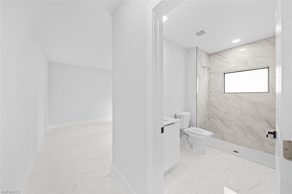 Bathroom featuring a walk-in shower with large format tile surround, a built-in shower window, and a white vanity with integrated sink