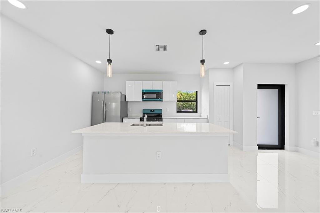 Open-concept kitchen with a central island, recessed lighting, stainless steel appliances, and a window providing natural light