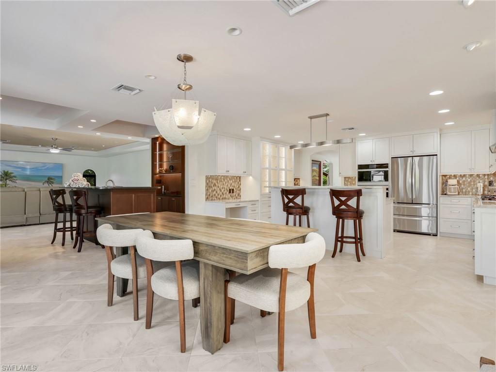 Spacious open-concept layout featuring light-toned tile flooring, recessed lighting, and a modern chandelier