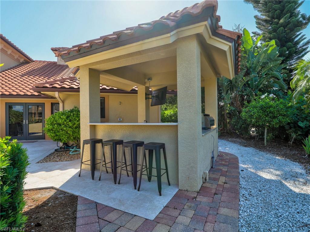 Outdoor kitchen featuring a built-in grill, bar seating, and a tile roof