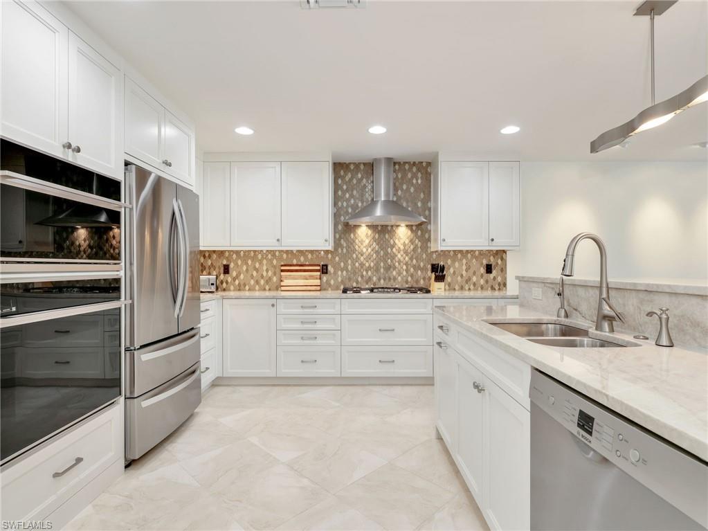 White shaker cabinetry, stainless steel appliances, patterned tile backsplash, light-toned countertop, and recessed lighting
