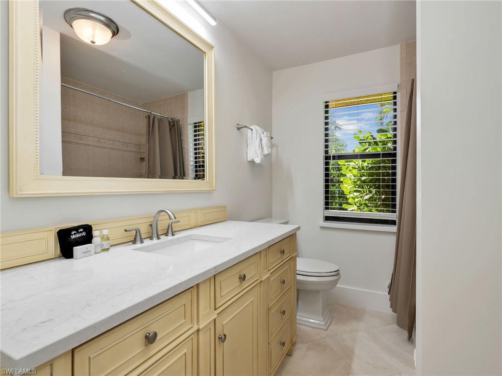Cream-colored vanity with a light-toned countertop, framed mirror, and chrome faucet