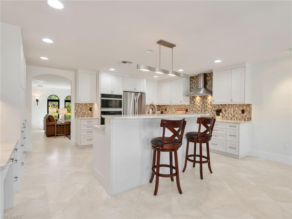 Kitchen featuring white cabinetry, stainless steel appliances, a center island, recessed lighting, and tile flooring
