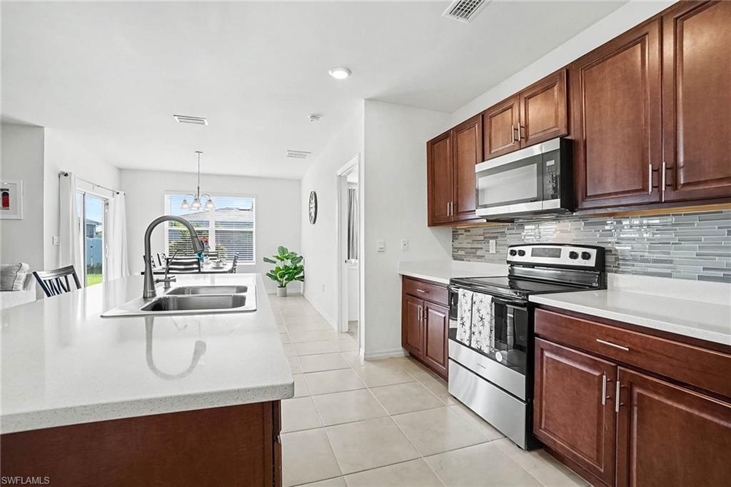 Kitchen featuring stainless steel appliances, wood-finish cabinetry, white countertops, and a tile backsplash