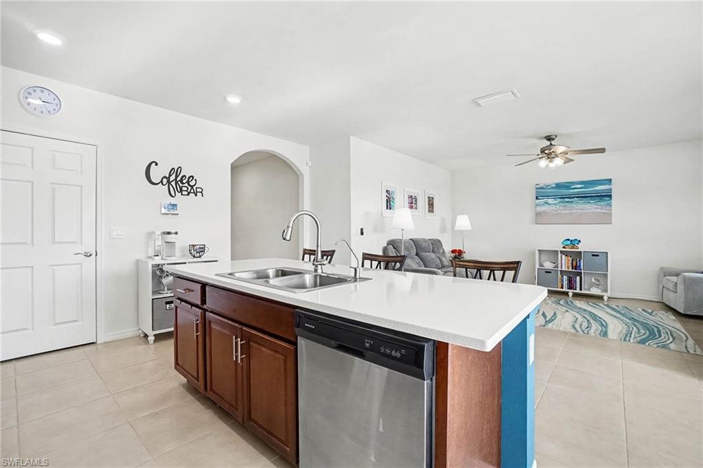 Kitchen island with a double basin sink, stainless steel dishwasher, and white countertop