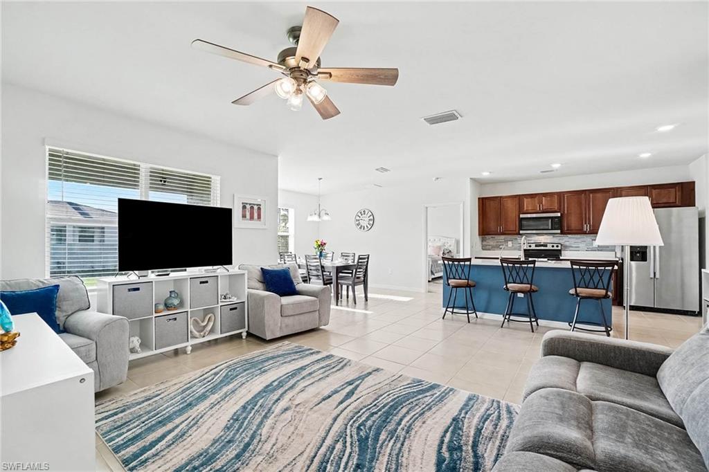 Open-concept living space with tile flooring, a ceiling fan, and large windows