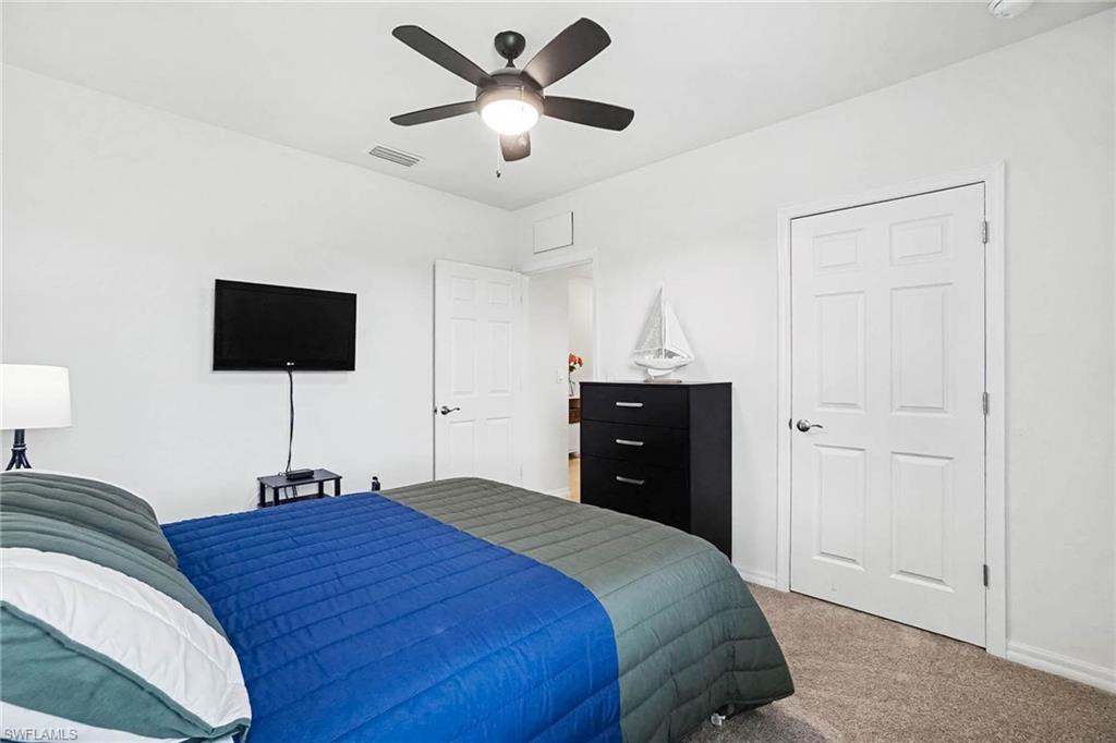 Carpeted flooring, white paneled doors, and a ceiling fan with integrated lighting