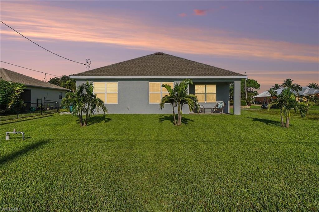 Expansive green lawn with established palm trees and a covered patio