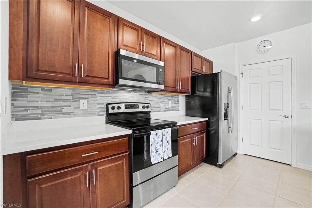 Kitchen featuring wood-finish cabinetry, a subway tile backsplash, white countertops, and stainless steel appliances