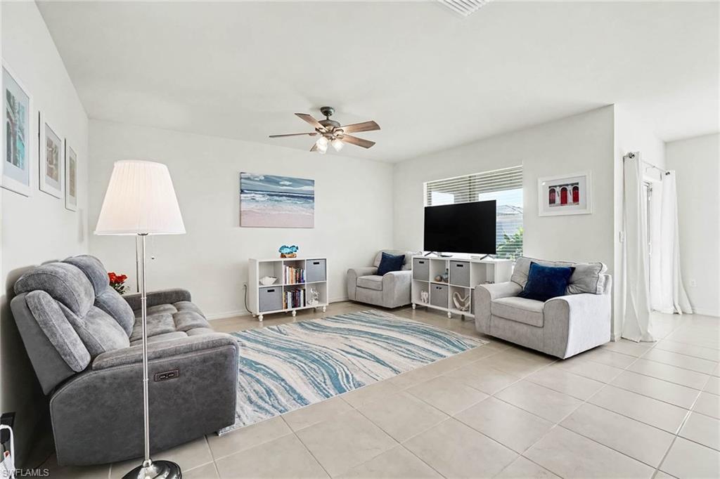 Neutral tile flooring, ceiling fan, white wall finishes, and a window with horizontal blinds