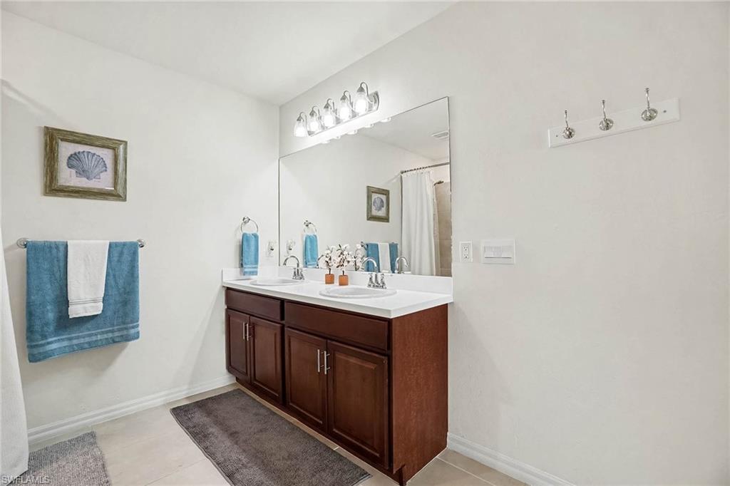 Dual vanity with white countertops, undermount sinks, and wood-finish cabinetry