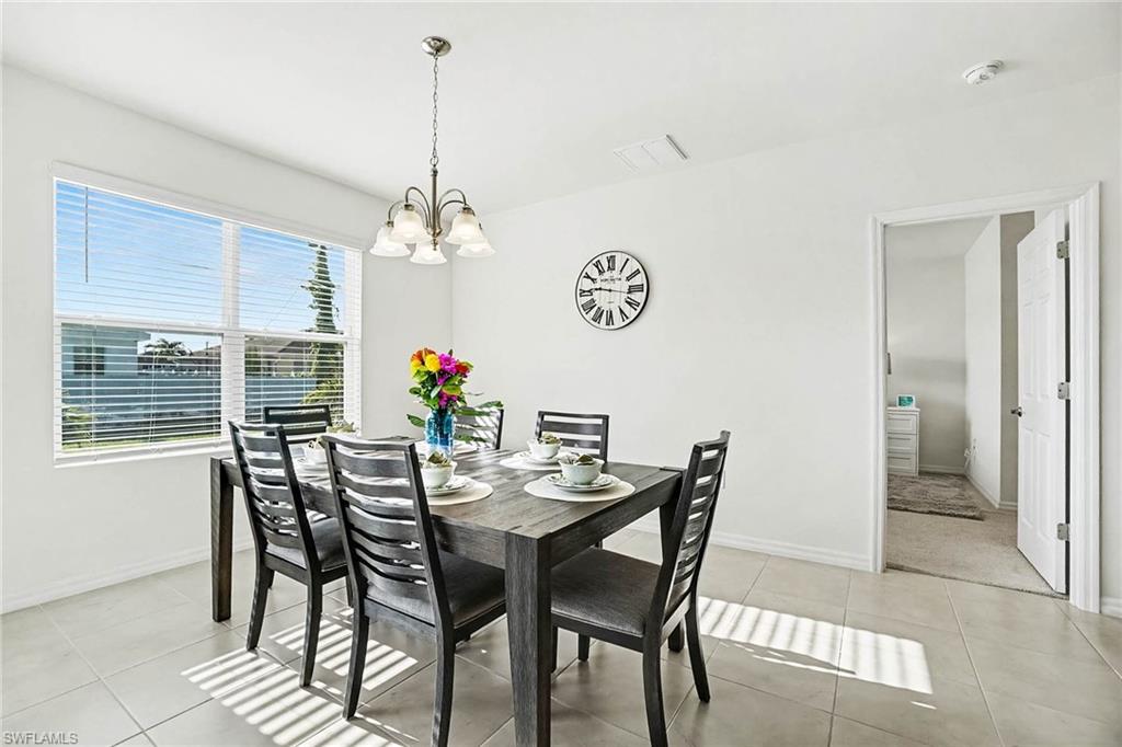 Dining area featuring tile flooring, a multi-pane window with blinds, and a ceiling-mounted chandelier