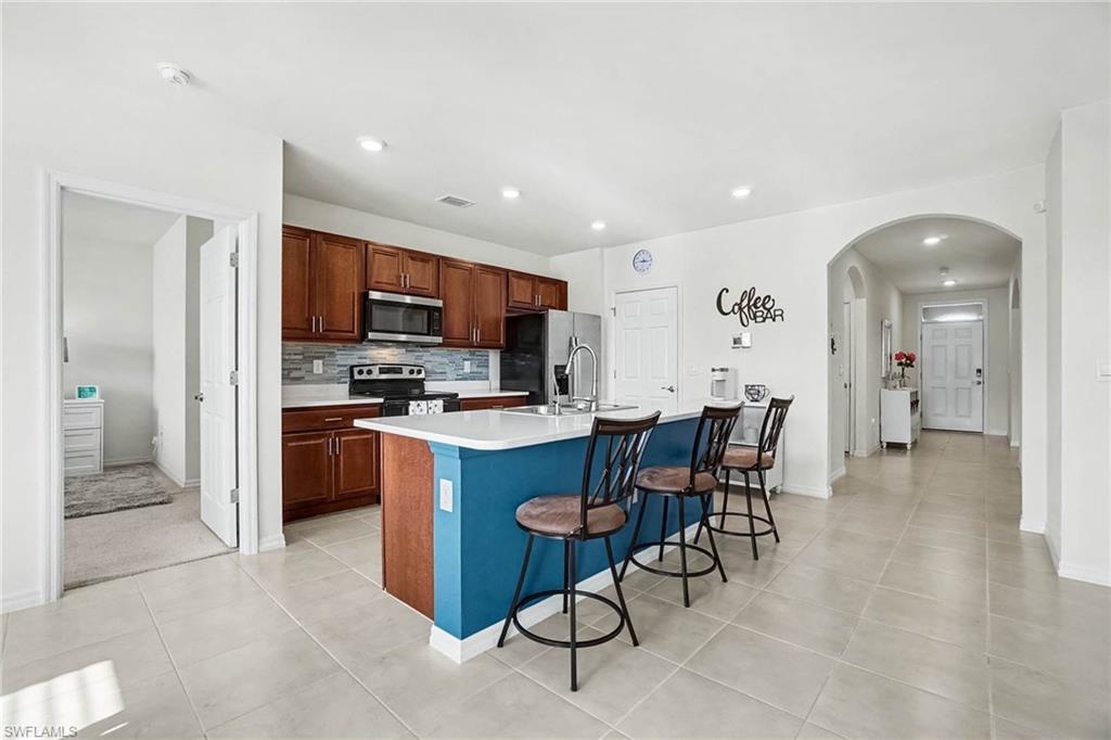 Kitchen featuring wood cabinetry, stainless steel appliances, a tile backsplash, and a central island with countertop seating