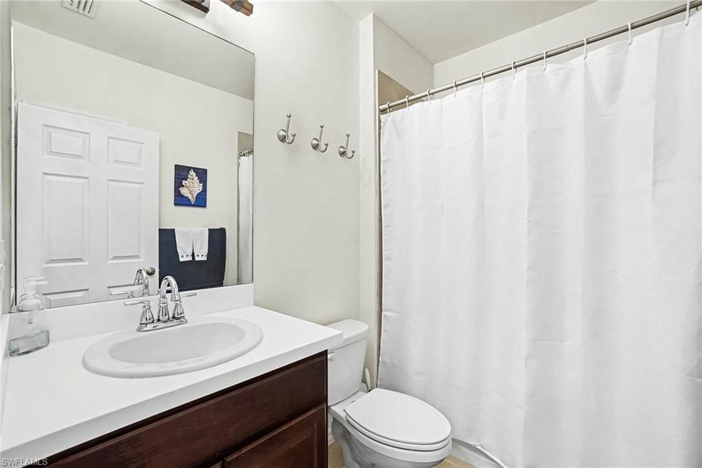 Vanity with a white countertop and integrated sink, chrome faucet, and dark wood-finish cabinetry