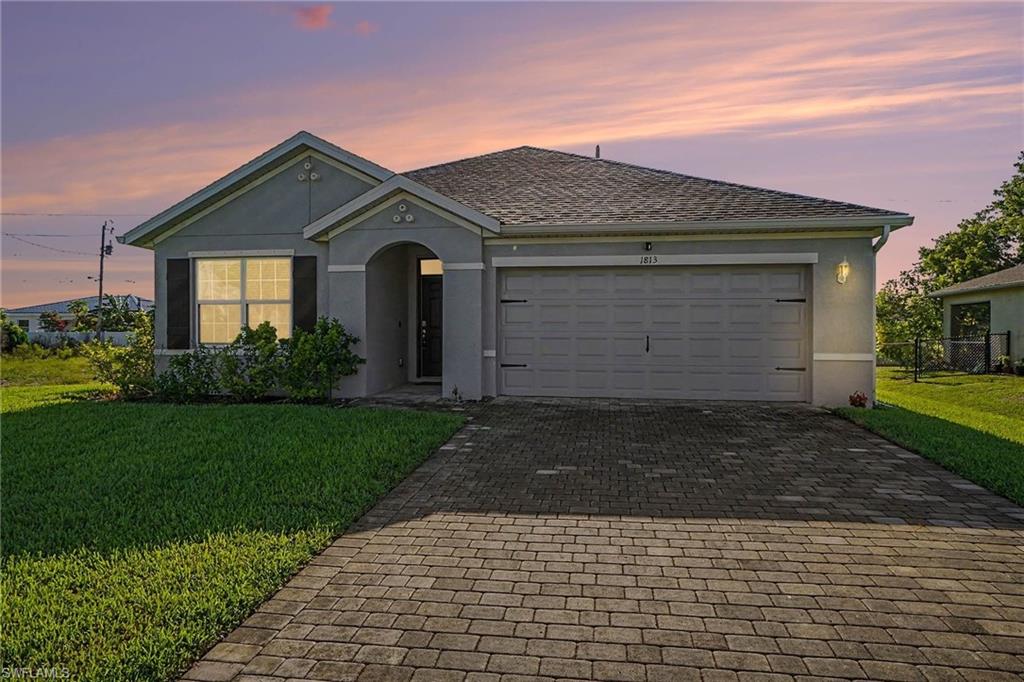 Single-story home featuring a stucco exterior, an attached garage, a paved driveway, and a covered entry
