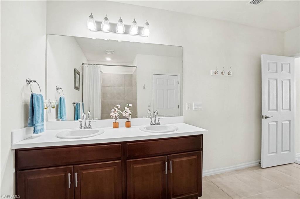 Dual vanity with white countertop, chrome fixtures, and wood-finish cabinetry
