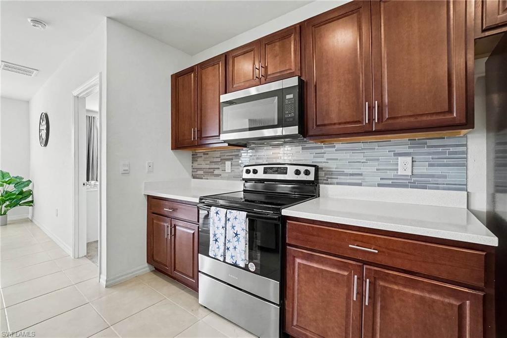 Kitchen featuring wood cabinetry, stainless steel appliances, a tile backsplash, and light-toned countertops