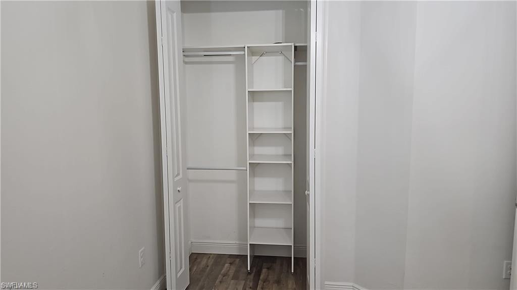 Closet with built-in shelving, two hanging rods, bi-fold doors, and wood-finish flooring