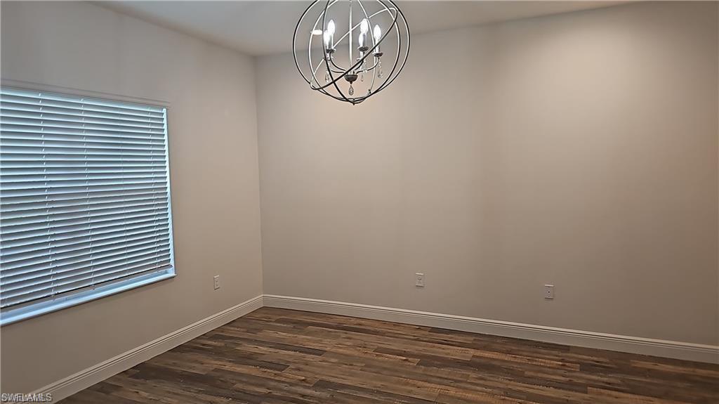 Wood-finish flooring, neutral wall tones, white trim, and a contemporary chandelier