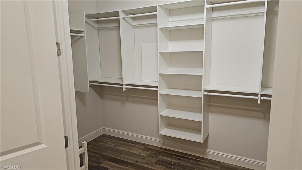 Custom closet system featuring multiple hanging rods, built-in shelving, and wood-finish flooring