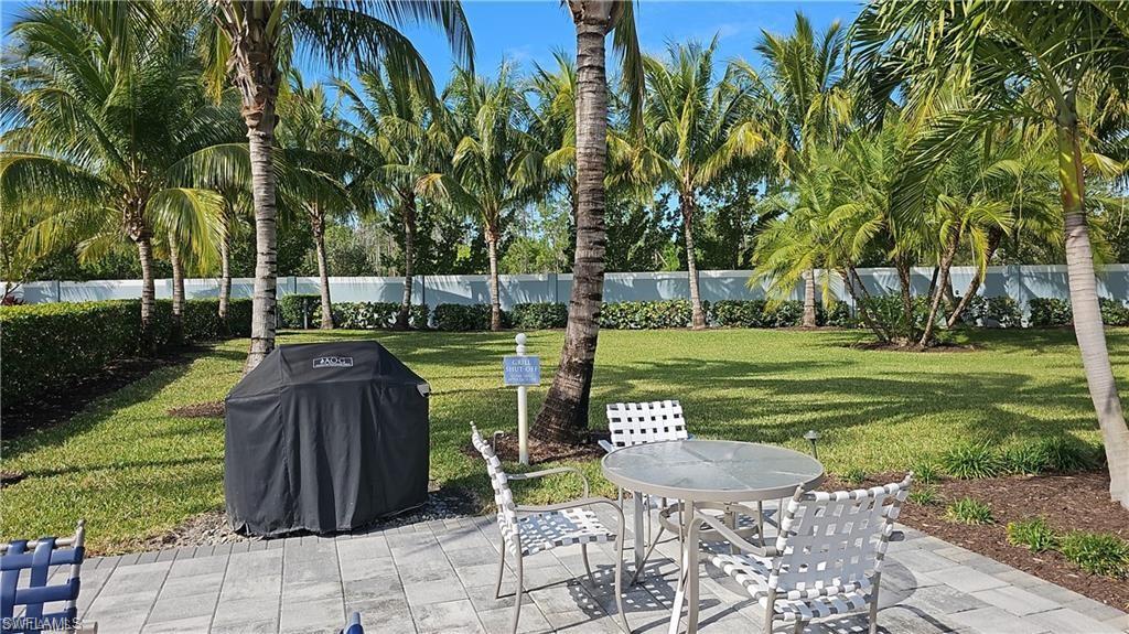 Paver patio with a landscaped yard, mature palm trees, and a privacy wall