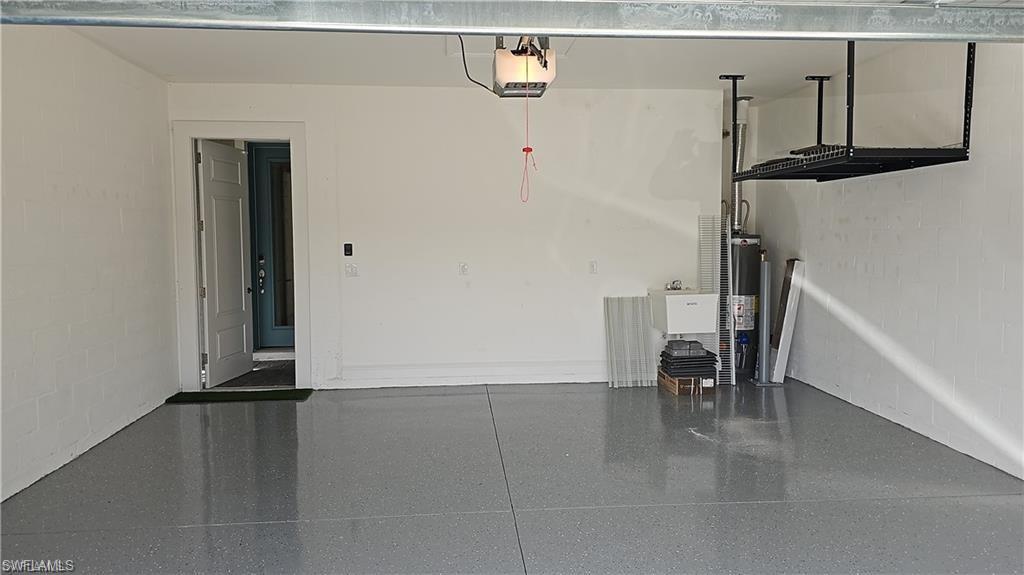 Garage with an epoxy floor finish, overhead storage racks, and a utility sink