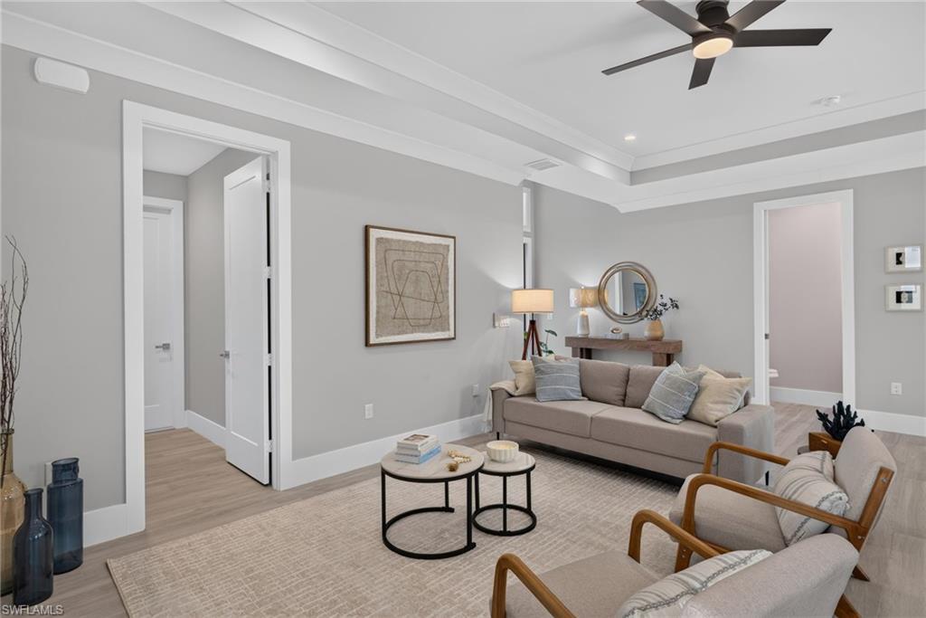 Tray ceiling with recessed lighting, wood-finish flooring, white trim, flat panel interior doors, and a ceiling fan