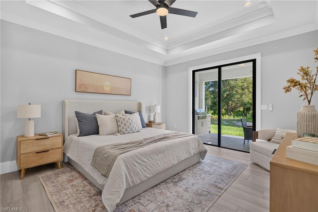 Tray ceiling with crown molding, ceiling fan, wood-finish flooring, sliding glass doors, and recessed lighting