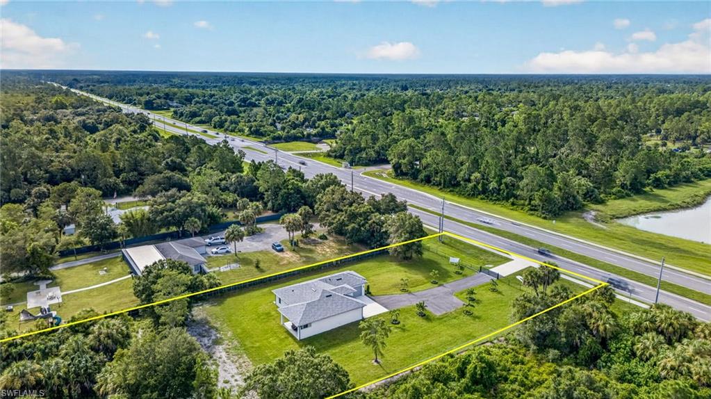 Expansive lot featuring a single-story structure, paved driveway, and mature landscaping