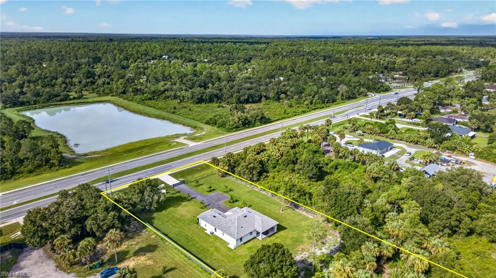 Aerial perspective showcasing a single-story residence with a gray shingle roof, surrounded by a expansive green lawn