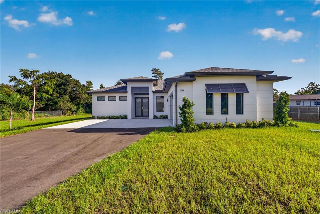 Contemporary architecture featuring a white exterior, dark gray roof, and a paved driveway