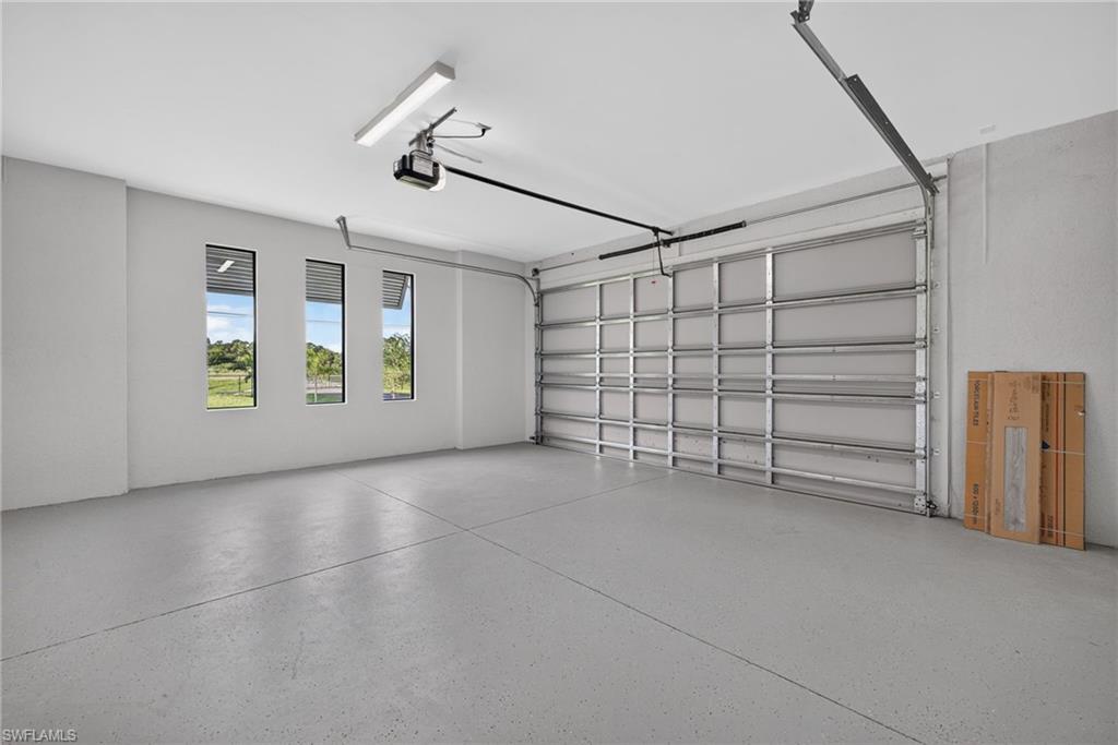 Spacious garage with an epoxy-coated floor, three vertical windows, and overhead lighting