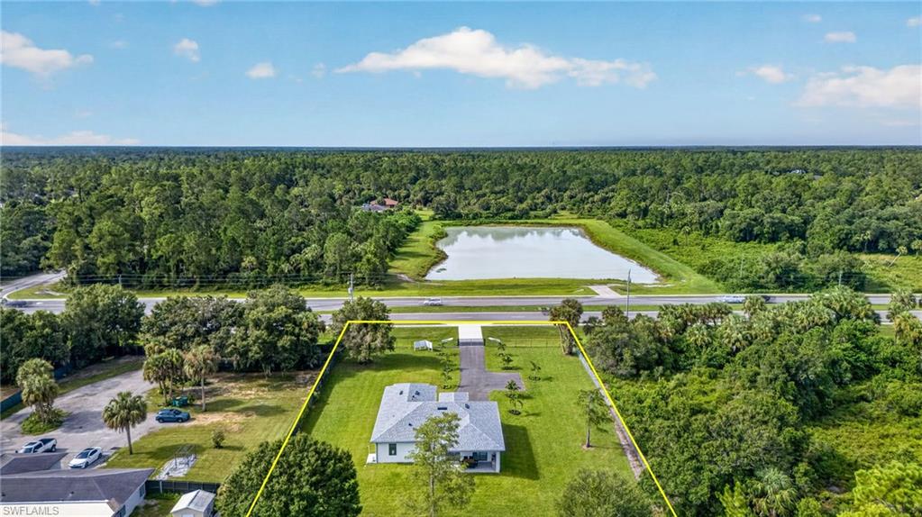 Expansive lot with a light-colored exterior residence, extensive green lawn, and mature trees