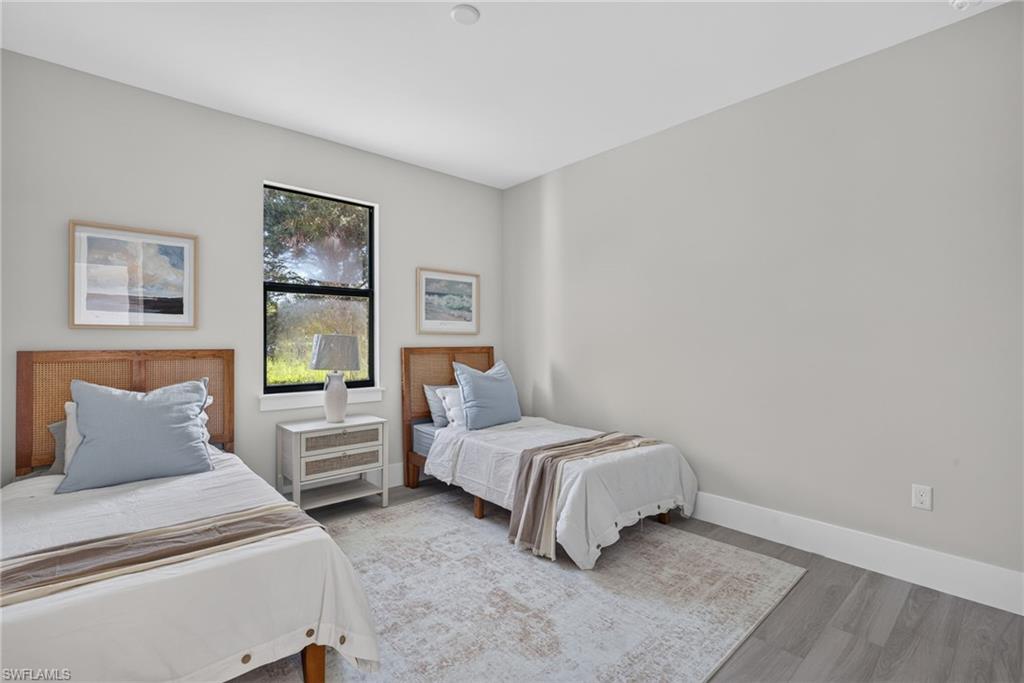 Light gray walls, contemporary window with black trim, and wood-finish flooring