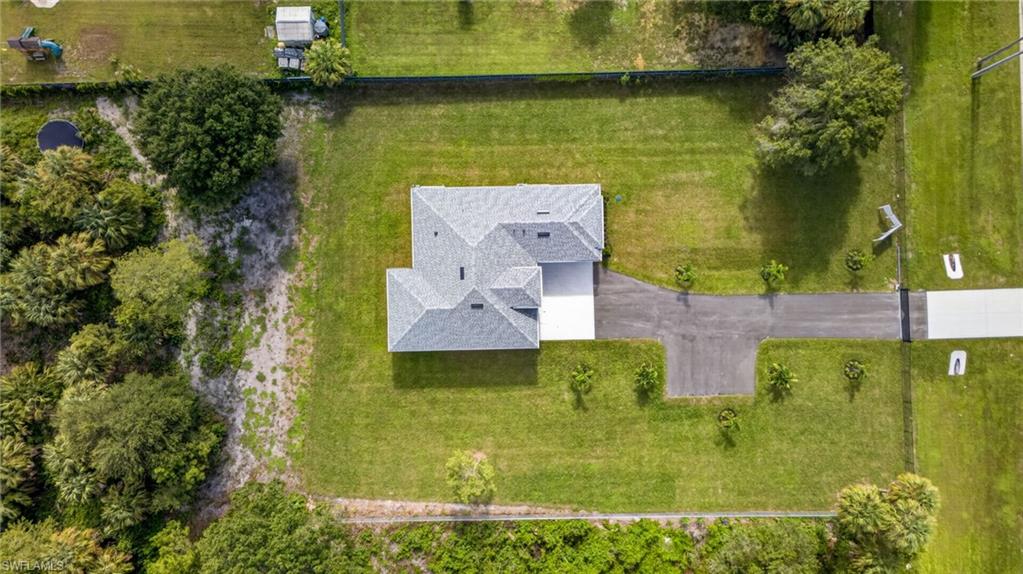 Expansive property with a well-maintained lawn, a paved driveway, and established trees